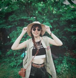 Young woman wearing sunglasses while standing against trees