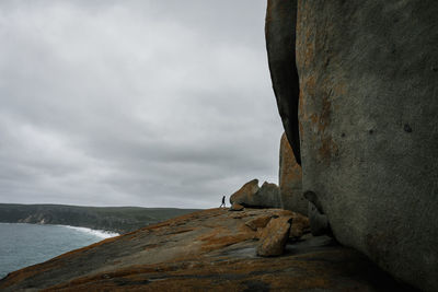 Low angle view of woman on rock formation against sky