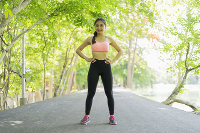 Full length of young woman exercising on road at park