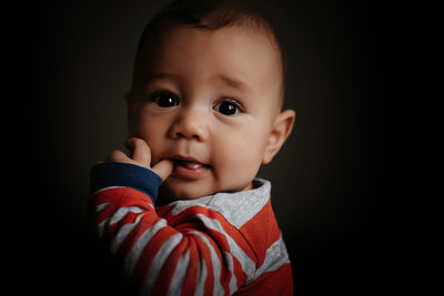Portrait of cute baby boy against black background