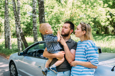 Mom, dad and little son in a convertible car. summer family road trip to nature