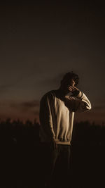 Young man looking away against sky at night