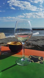 Close-up of beer on table against sea