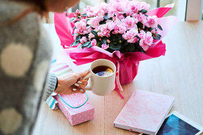 Midsection of woman holding coffee cup on table