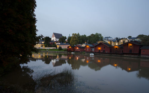 Houses by lake against clear sky