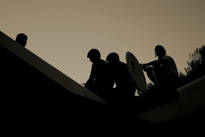 Low angle view of silhouette men against clear sky