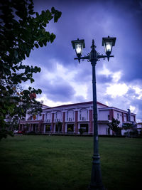 Street light on field by building against sky