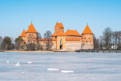 Medieval castle of trakai, vilnius, lithuania in winter with frozen lake and ukrainian flag