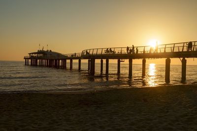 Pier over sea against clear sky during sunset