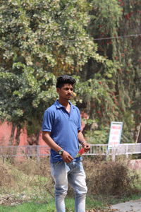 Young man looking away while standing in park