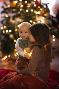 Baby and her older sister on the background of the christmas tree, the concept of christmas and