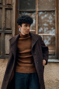 Portrait of young woman standing against wall
