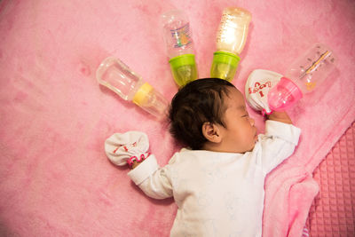 Directly above shot of baby sleeping on bed with milk bottles at home