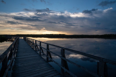 Pier over lake against sky during sunset