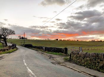 Road by landscape against sky during sunset