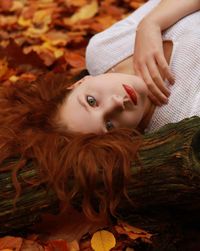 Portrait of young woman with long hair lying down on field