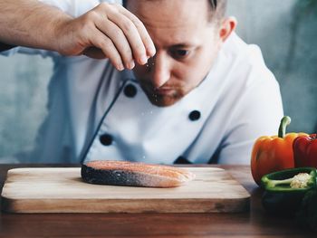 Close-up of male chef seasoning raw fish on table