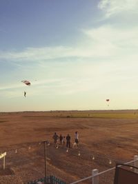 People flying over landscape against sky