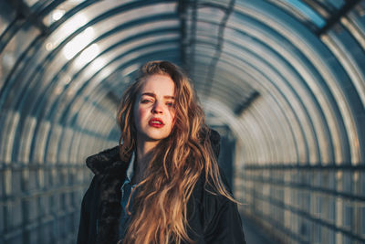 Beautiful young woman standing against curtain