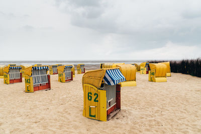 Hooded chairs on beach against sky