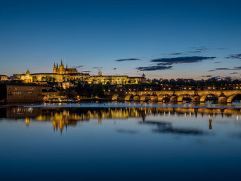 Illuminated prague castle by charles bridge over vltava river