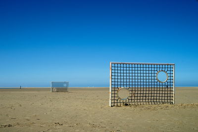 Lifeguard hut on beach against clear blue sky