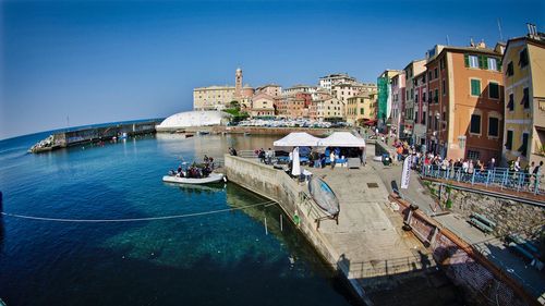 Buildings by sea against clear blue sky