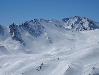 Scenic view of snowcapped mountains against clear blue sky