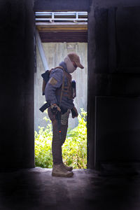 Side view of man standing against door