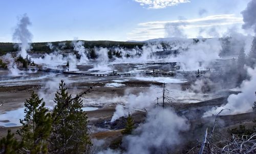 Smoke emitting from volcanic landscape against sky