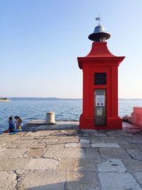 Lighthouse in front of sea against clear sky