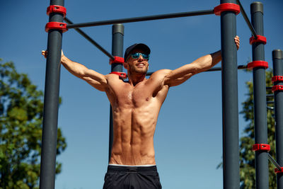 Shirtless muscular man exercising in playground