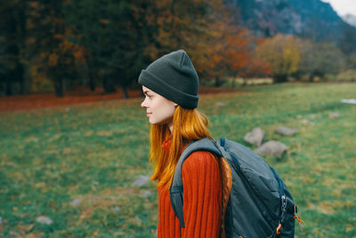 Full length of young woman standing in park during autumn