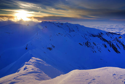 Scenic view of snowcapped mountains against sky during sunset