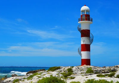 Lighthouse by sea against sky