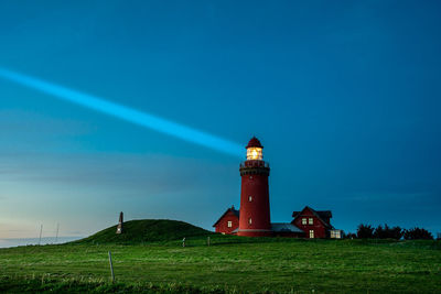 Lighthouse on field against sky during dusk