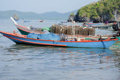 Fishing boats moored in sea against sky