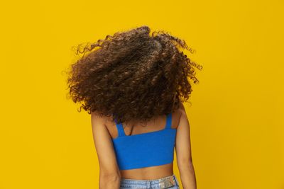 Rear view of woman against yellow background