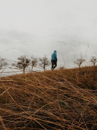 Man walking on field against sky