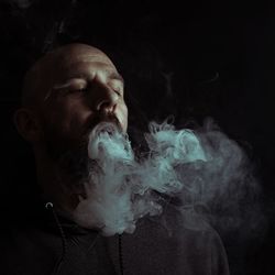 Portrait of young man smoking over black background