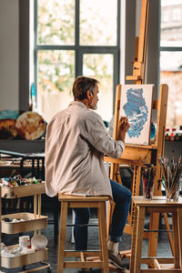 Rear view of man sitting on table