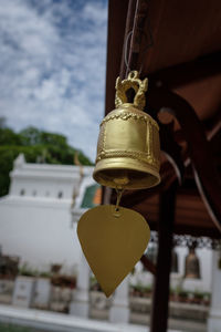 Low angle view of yellow bell hanging outside building