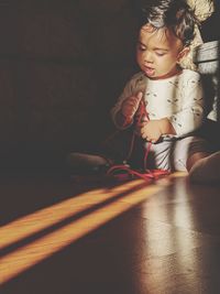 Baby looking away while sitting on floor at home