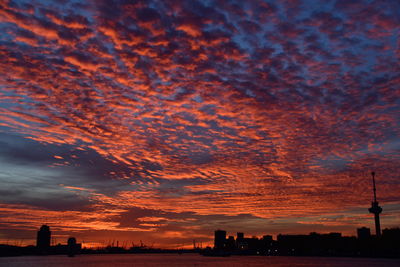 Silhouette of buildings against cloudy sky during sunset