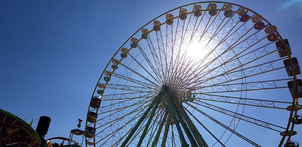 Low angle view of ferris wheel against clear blue sky