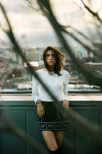 Portrait of young woman standing against wall