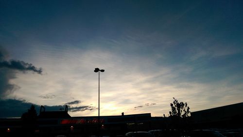 Silhouette of buildings against cloudy sky at sunset