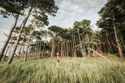 Woman standing on field against trees at forest