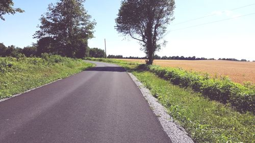 Road amidst field against clear sky