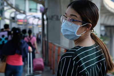 Rear view of woman wearing flu mask at airport